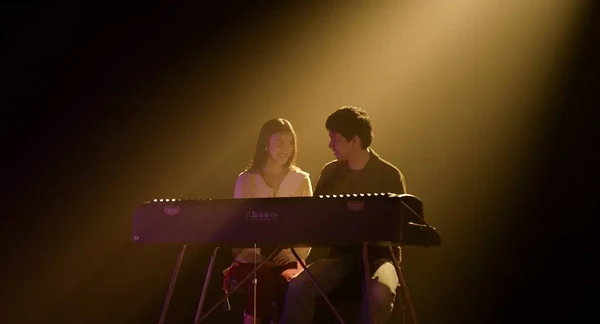 Rangga and Cinta share a moment on stage with a keyboard in Rangga & Cinta.
