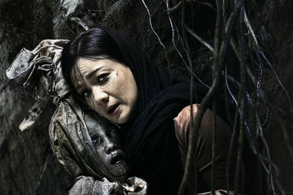 A woman looks terrified beside a mysterious child figure in "Panggilan dari Kubur".