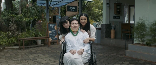 Family poses outside a cafe with a man in wheelchair in "Hanya Namamu dalam Doaku".