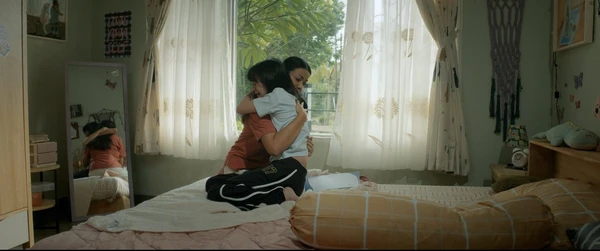 Two characters share a hug in a bedroom in "Hanya Namamu dalam Doaku".